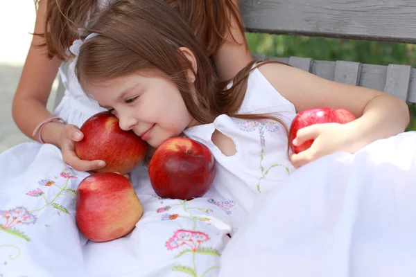 Όμορφα κορίτσια με καλάθι με κόκκινα μήλα σε ένα παγκάκι — Φωτογραφία Αρχείου