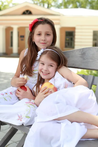 Meninas encantadoras com cesta de maçãs vermelhas em um banco — Fotografia de Stock