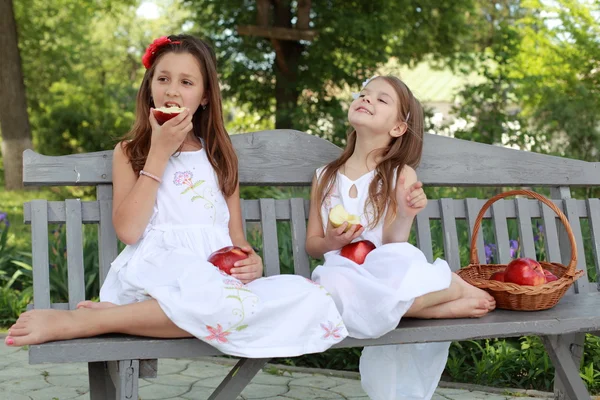Piękne dziewczyny z kosz czerwonych jabłek na ławce — Zdjęcie stockowe