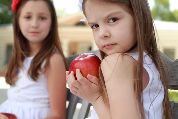 สาวน่ารักที่มีตะกร้าแอปเปิ้ลสีแดงบนม้านั่ง — ภาพถ่ายสต็อก