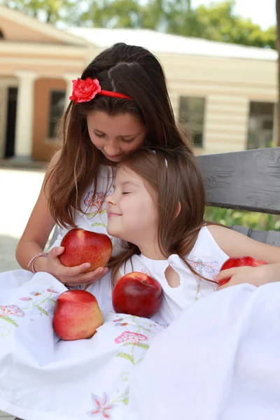 Chicas encantadoras con manzanas rojas en un banco —  Fotos de Stock