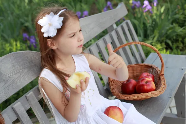 Lovely girls with basket of red apples on a bench — Stok fotoğraf