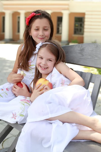 Meninas encantadoras com cesta de maçãs vermelhas em um banco — Fotografia de Stock