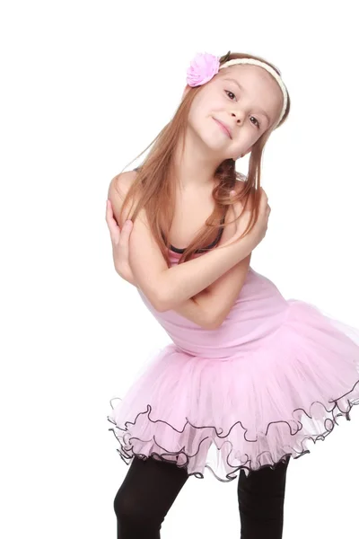 Портрет улыбающейся маленькой танцовщицы в розовой пачке, стоящей в балетной позе — стоковое фото