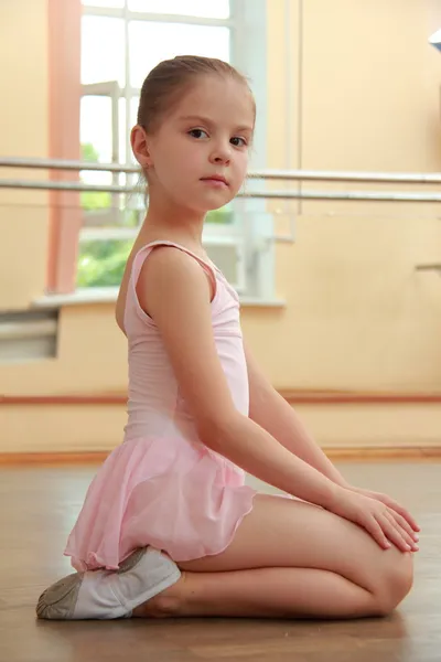 Ginasta jovem bonito em um terno para o ginásio aquecendo no chão de madeira no salão de ballet — Fotografia de Stock