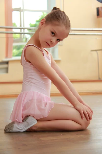 Smilende ballerina i en tutu og poengende posering foran kamera i en ballettklasse – stockfoto