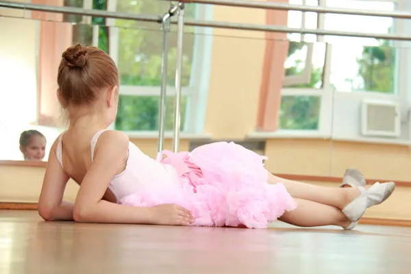 Mignon jeune gymnaste en costume pour le gymnase échauffement sur le sol en bois dans la salle de ballet — Photo