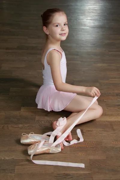 Jong meisje die zich bezighouden met een roze ballet tutu en pointe in de ballet hal op de houten dansvloer — Stockfoto