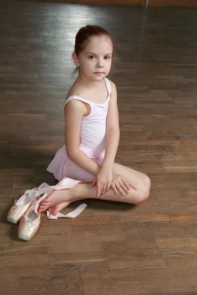 Молодая балерина надевает пуанты в балетном классе на старом деревянном танцполе — стоковое фото