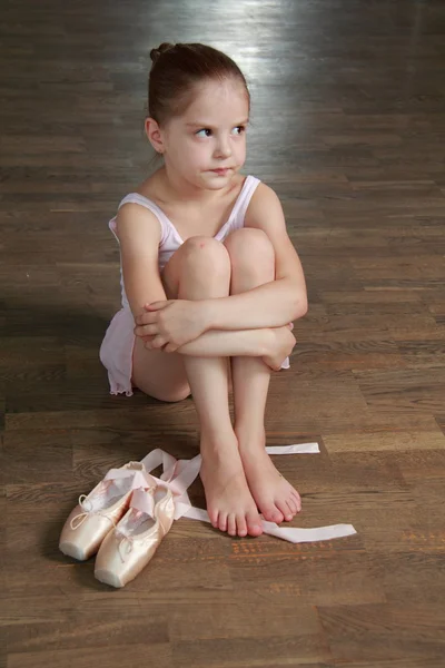 Bailarina sonriente europea sentada en un viejo suelo de madera con zapatos de ballet — Foto de Stock