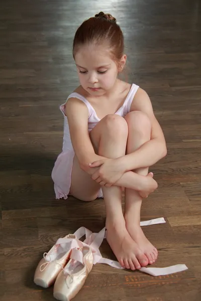Europese lachende ballerina zittend op een oude houten vloer dragen van ballet schoenen — Stockfoto
