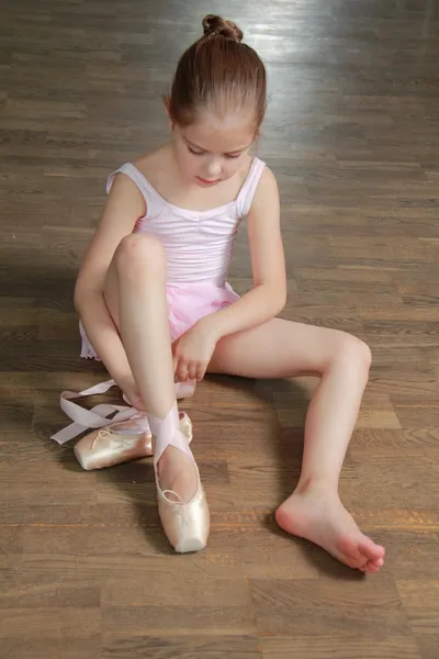 Giovane ragazza impegnata in un tutù di balletto rosa e punta nella sala da ballo sulla pista da ballo in legno — Foto Stock