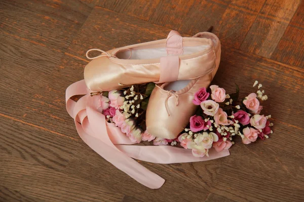 Pointe shoes with ribbons and a bouquet of flowers on a background of the old wooden floor — Stock Photo, Image