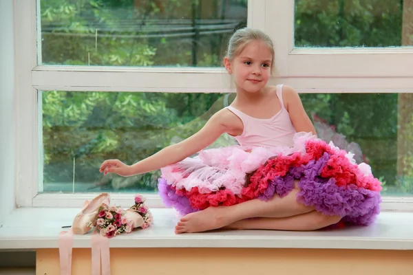 Jovem dançarina de balé sorridente com sapatos pontiagudos e flores sentadas em um peitoril da janela — Fotografia de Stock