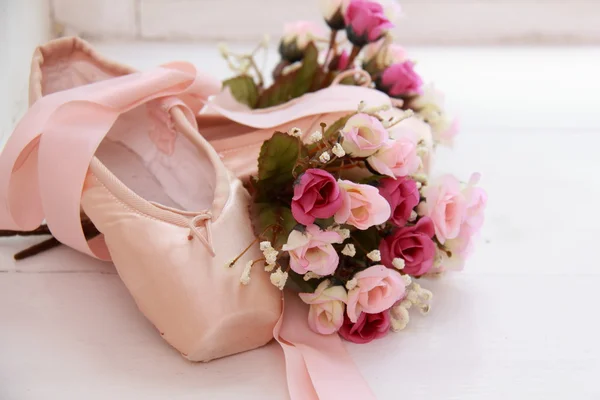 Children pink pointe with ribbons lay on the windowsill next to white flowers — Stock Photo, Image