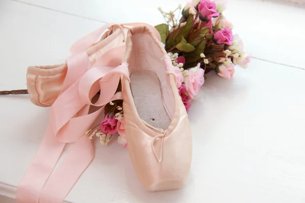 Children pink pointe with ribbons lay on the windowsill next to white flowers — Stock Photo, Image