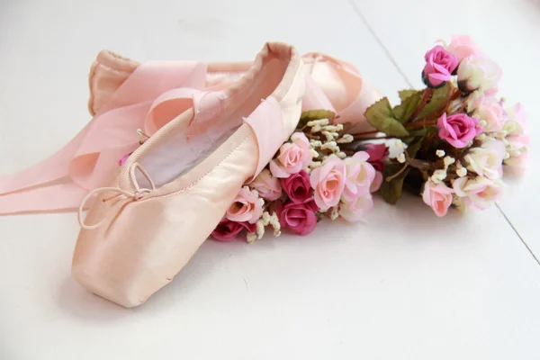 Children pink pointe with ribbons lay on the windowsill next to white flowers — Stock Photo, Image