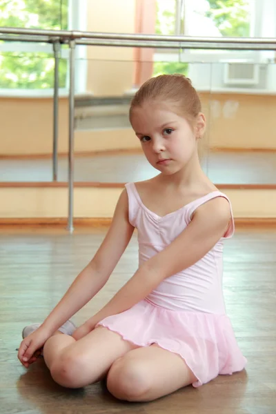 Jong meisje die zich bezighouden met een roze ballet tutu en pointe in de ballet hal op de houten dansvloer — Stockfoto