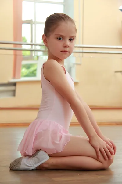 Menina jovem envolvida em um tutu balé rosa e ponteiro no salão de balé na pista de dança de madeira — Fotografia de Stock