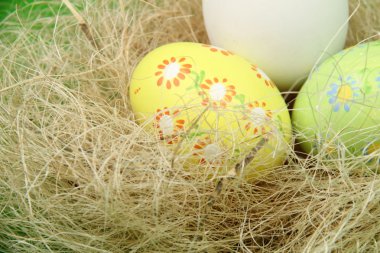 saman yapılmış sepet içinde çizimleri ile renkli yumurta boyalı