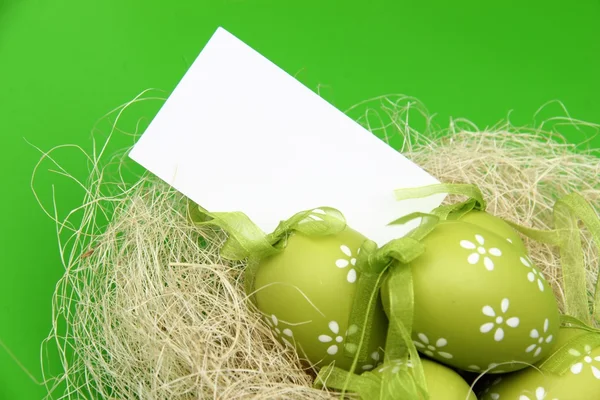 Цветное яйцо с узором в пасхальной корзине и чистым листом для поздравления с праздником — стоковое фото
