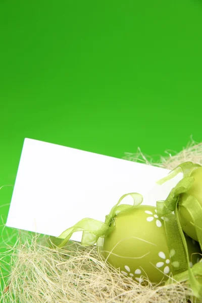 Huevo de color con un patrón en la cesta de Pascua y una hoja en blanco para el texto de saludo en vacaciones — Foto de Stock