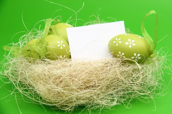 Kolorowe jajka ze wzorem w wielkanocnym koszyku i pusty arkusz dla tekst powitania na wakacje — Zdjęcie stockowe