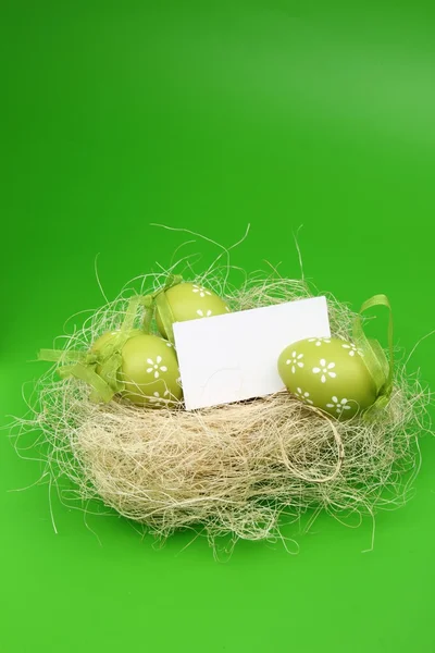 Uovo con un motivo nel cestino di Pasqua e un foglio bianco per il testo di saluto su sfondo verde — Foto Stock