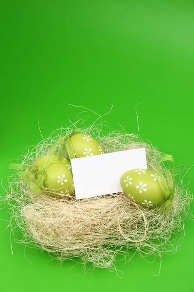 Uovo colorato con un motivo nel cestino di Pasqua e un foglio bianco per il testo di saluto in vacanza — Foto Stock