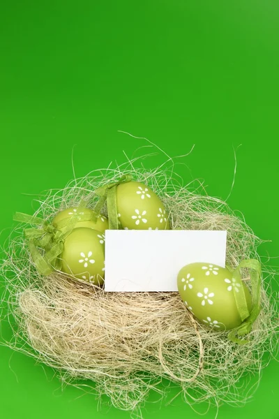 Зеленое яйцо с узором в пасхальной корзине и чистым листом для приветствия текста — стоковое фото