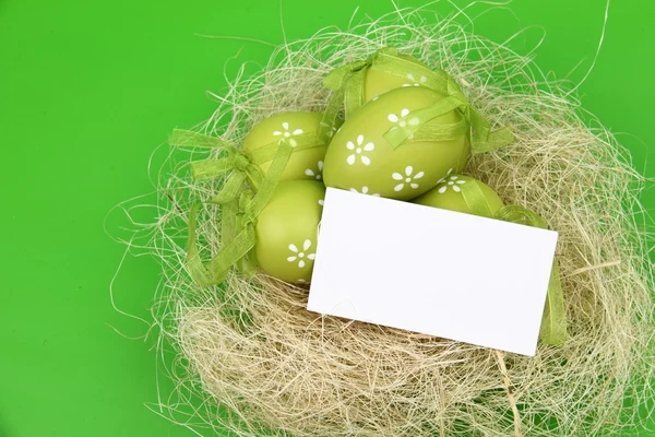 Зеленое яйцо с узором в пасхальной корзине и чистым листом для приветствия текста — стоковое фото
