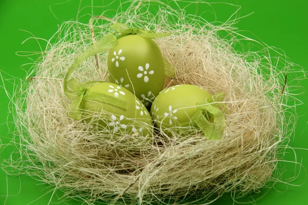 Изображение зеленого яйца с узором в пасхальной корзине на зеленом фоне — стоковое фото