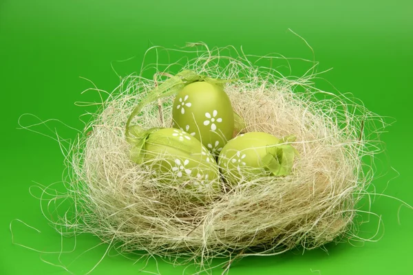 Image of a green egg with a pattern in the Easter basket on green background — Stock Photo, Image