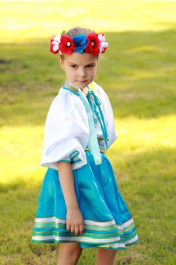 parlak bir ulusal kostüm Ukrayna yaz park yeşil çim zemin üzerinde değil, küçük kız gülümseyerek