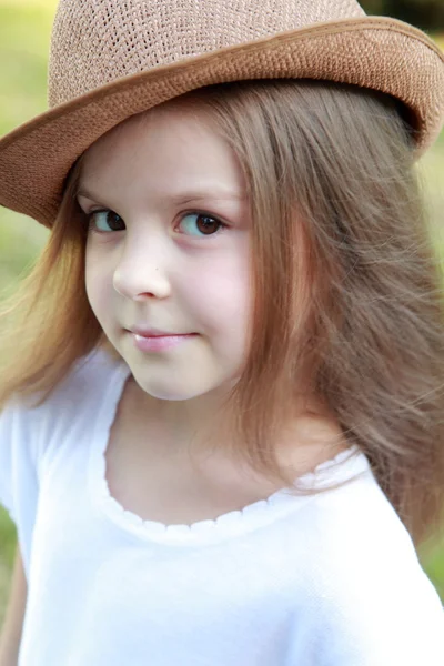 Schöne kleine Mädchen in einem weißen Kleid und Hut im Freien — Stockfoto