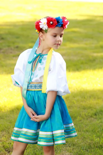 Smiling little girl in a bright national costume Ukraine is on the background of green grass in the summer park — Stock Photo, Image