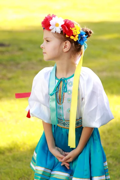 Roztomilá holčička s okouzlujícím úsměvem v krásném národním kroji Ukrajina je na pozadí zelené trávy venku — Stock fotografie