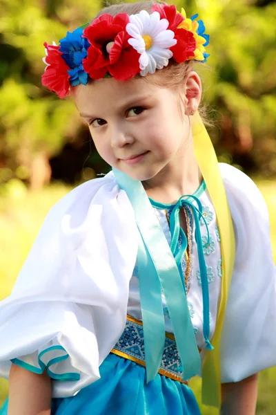 Güzel bir ulusal kostüm büyüleyici bir gülümsemeyle şirin küçük kız Ukrayna yeşil çim açık havada arka plan üzerinde olduğunu. — Stok fotoğraf