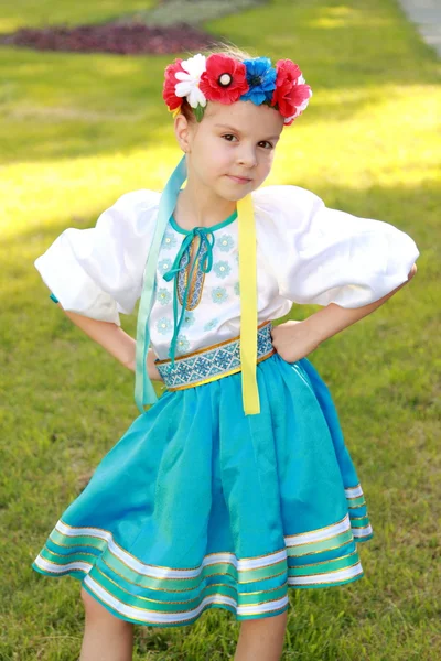 Smiling little girl in a bright national costume Ukraine is on the background of green grass in the summer park — Stock Photo, Image