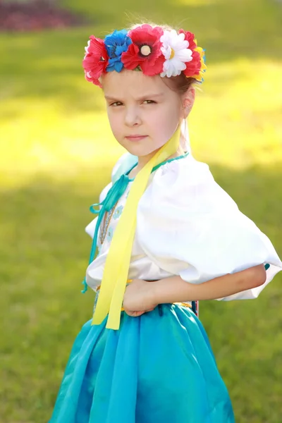 Sonriente niña en un traje nacional brillante Ucrania está en el fondo de la hierba verde en el parque de verano —  Fotos de Stock