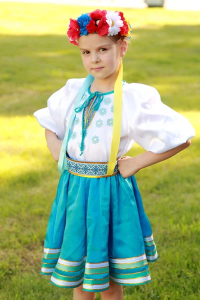 Мила маленька дівчинка з чарівною усмішкою в красиві Національний костюм Україна – на фоні зеленої трави на відкритому повітрі — стокове фото