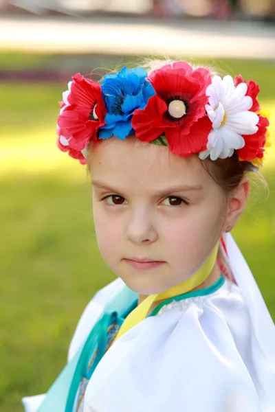 Smiling little girl in a bright national costume Ukraine is on the background of green grass in the summer park — Stock Photo, Image