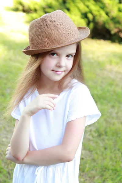 Adorable petite fille avec un chapeau posant à la caméra dans le parc d'été en plein air — Photo