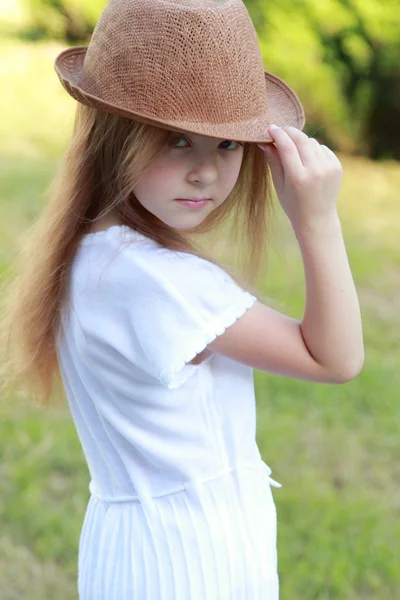 Bedårande liten flicka med en hatt som poserar på kameran i sommaren park utomhus — Stockfoto