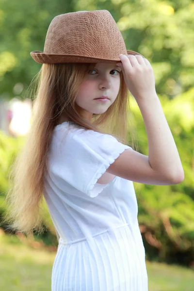 Caucasiano menina sorridente em um vestido branco e um chapéu ao ar livre — Fotografia de Stock
