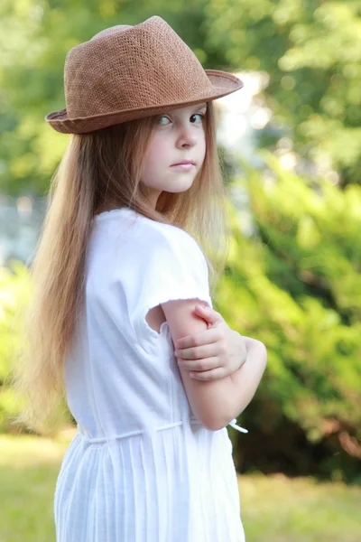 Vacker liten flicka i en vit klänning och hatt utomhus — Stockfoto