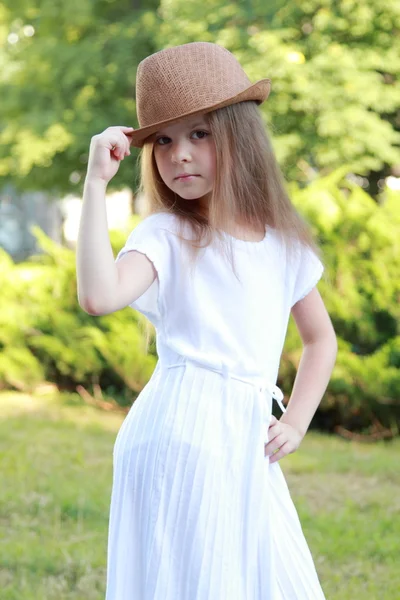 Mooi meisje in een witte jurk en hoed in de buitenlucht — Stockfoto