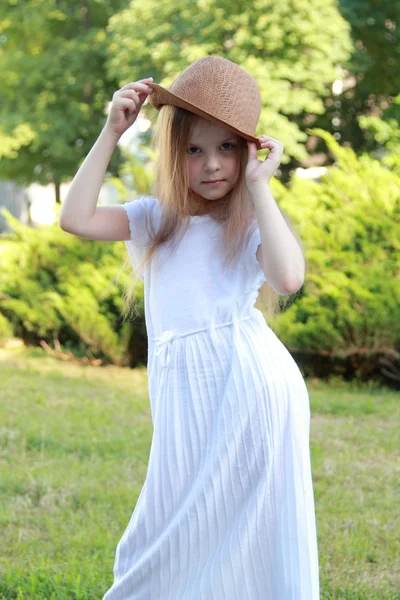 Caucasiano menina sorridente em um vestido branco e um chapéu ao ar livre — Fotografia de Stock