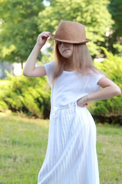 Entzückendes kleines Mädchen mit Hut posiert im Sommerpark im Freien vor der Kamera — Stockfoto