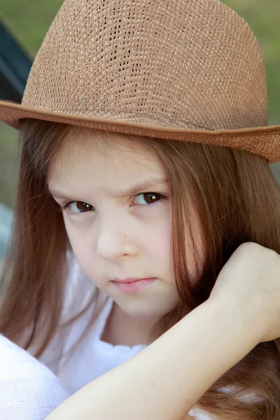 Adorable little girl with a hat posing at the camera in summer park outdoors — Stock Photo, Image